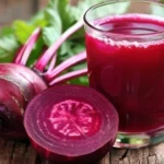 : Freshly made beetroot juice in a glass, surrounded by sliced beets and a sprig of parsley.