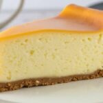 Classic New York Cheesecake with a rich, creamy texture and buttery graham cracker crust, beautifully plated for a delicious dessert experience.